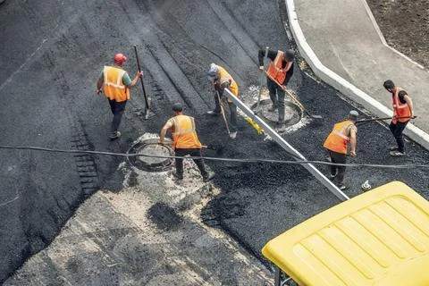 Workers lay a new asphalt coating using hot bitumen. Work of heavy machiner.. Stock Photos