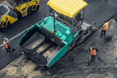 Workers lay a new asphalt coating using hot bitumen. Work of heavy machiner.. Stock Photos