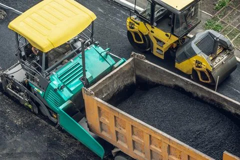 Workers lay a new asphalt coating using hot bitumen. Work of heavy machiner.. Stock Photos