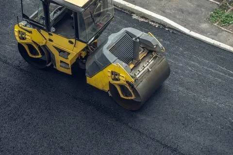 Workers lay a new asphalt coating using hot bitumen. Work of heavy machinery  Stock Photos