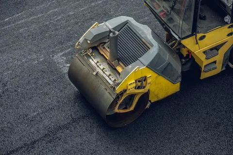 Workers lay a new asphalt coating using hot bitumen. Work of heavy machinery  Stock Photos