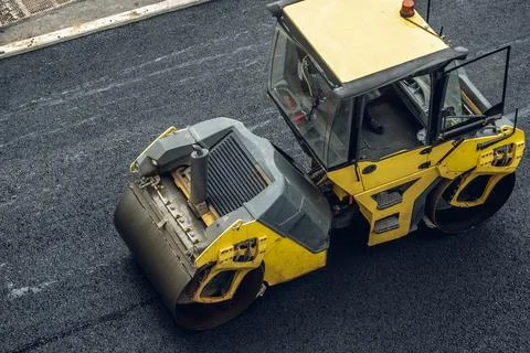 Workers lay a new asphalt coating using hot bitumen. Work of heavy machinery  Stock Photos