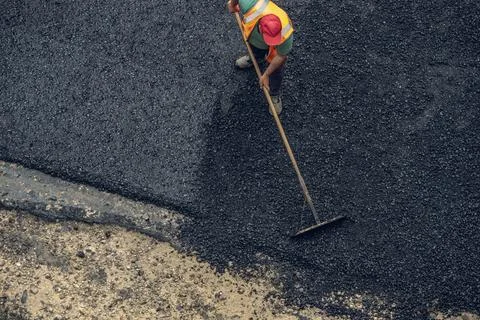 Workers lay a new asphalt coating using hot bitumen. Work of heavy machinery  Stock Photos