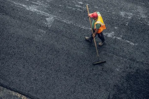 Workers lay a new asphalt coating using hot bitumen. Work of heavy machinery  Stock Photos