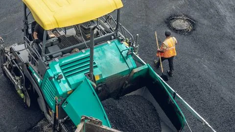 Workers lay a new asphalt coating using hot bitumen. Work of heavy machinery  Stock Photos