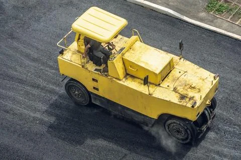 Workers lay a new asphalt coating using hot bitumen. Work of heavy machinery  Stock Photos