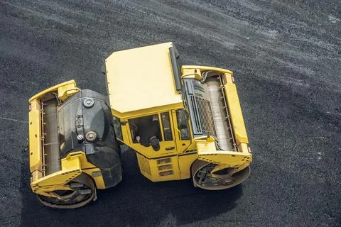 Workers lay a new asphalt coating using hot bitumen. Work of heavy machinery  Stock Photos