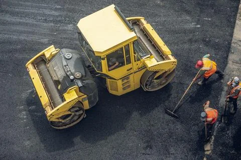 Workers lay a new asphalt coating using hot bitumen. Work of heavy machinery  Stock Photos
