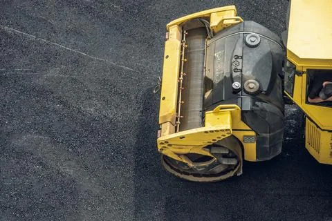 Workers lay a new asphalt coating using hot bitumen. Work of heavy machinery  Stock Photos