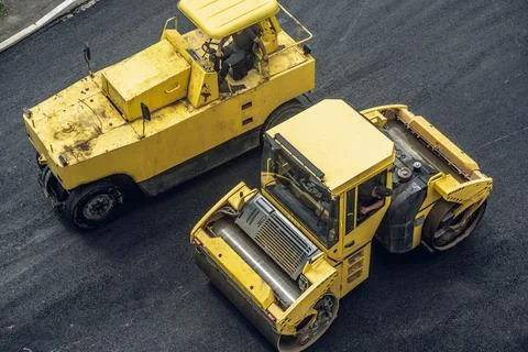 Workers lay a new asphalt coating using hot bitumen. Work of heavy machinery  Stock Photos