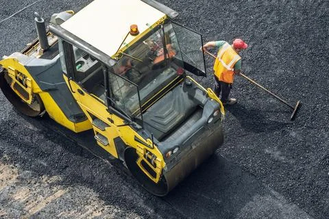 Workers lay a new asphalt coating using hot bitumen. Work of heavy machiner.. Stock Photos