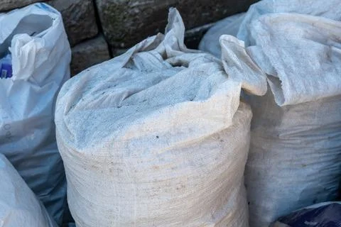 Workers left bags filled with materials near a stone wall during the aftern.. Stock Photos