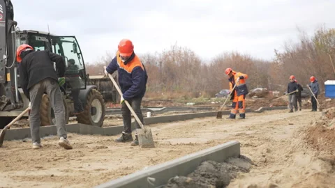 Workers level sand on construction site using large shovels Stock Footage 310245072