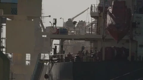 Workers load cargo on a ship at a busy port during the late afternoon Stock Footage 334626532