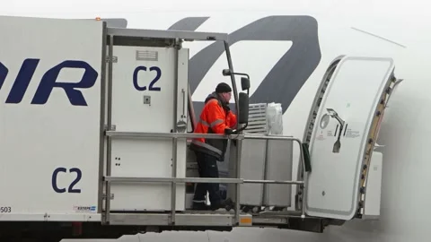Workers load carts to an airliner at the snowy Helsinki Airport, Finland Stock Footage 208840820