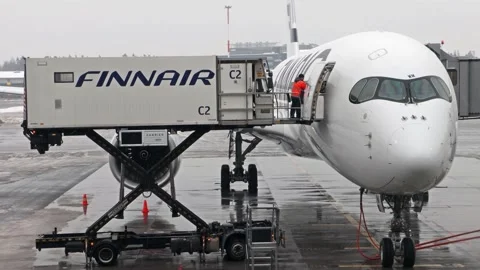 Workers load carts to an airliner at the snowy Helsinki Airport, Finland Stock Footage 214224445