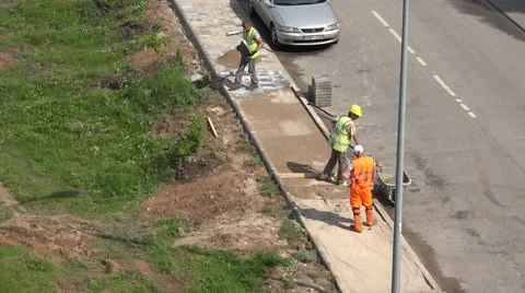Workers load sand into wheelbarrow and pave lay tiles. 4K Stock Footage 56847108