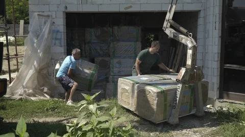 Workers loading packed of insulation materials on truck crane, construction site 動画素材 98760326