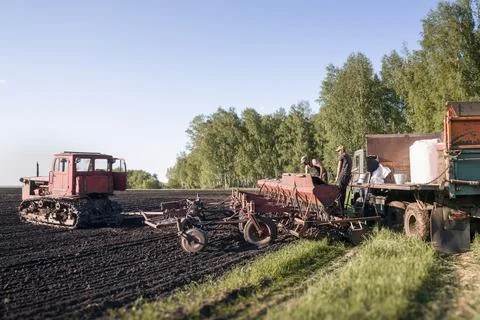 Workers Loading Seeds and Nitrogen Fertilizer into Seed Drill Near Tracked .. Stockfoto's