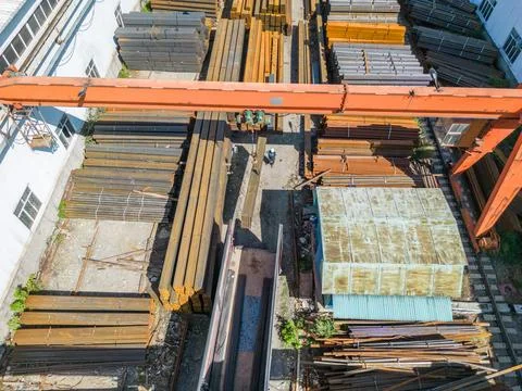 Workers loading stack of metal pipes with gantry crane into the truck Stock Photos