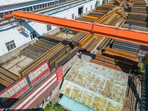 Workers loading stack of metal pipes with gantry crane into the truck Stock Photos