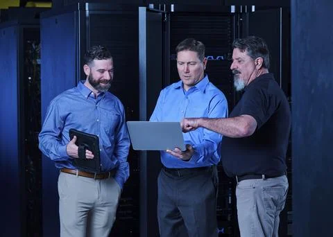 Workers looking at laptop in data center Stock Photos