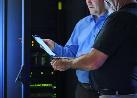 Workers looking at laptop in data center Stock Photos