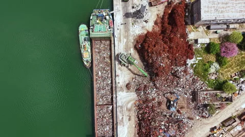 Workers manage a large pile of scrap metal near a dock while a barge is loaded Stock Footage 340148751