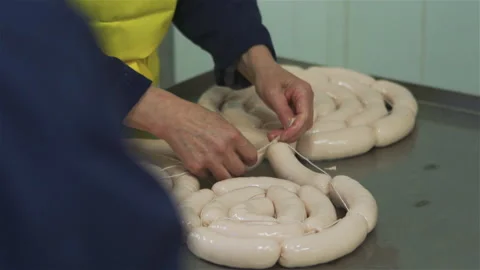 Workers in meat factory forming many short sausages from one long sausage. Sausa Stock Footage 131864587