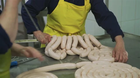 Workers in meat factory forming many short sausages from one long sausage. Stock Footage 131865050