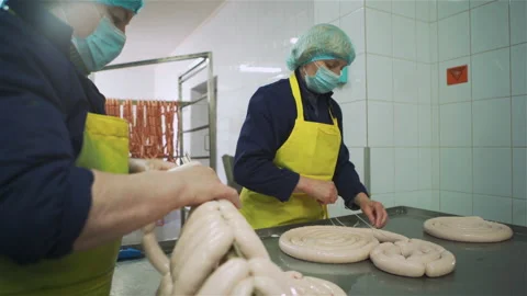 Workers in meat factory forming many short sausages from one long sausage. Sausa 库存影片 131865539
