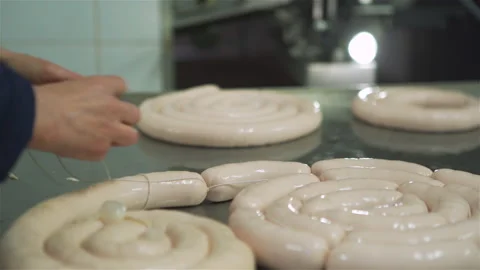 Workers in meat factory forming many short sausages from one long sausage. 库存影片 131866010