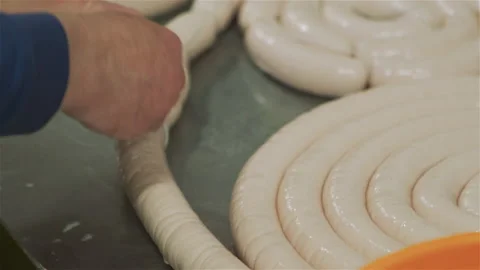Workers in meat factory forming many short sausages from one long sausage. Video stock 131868532