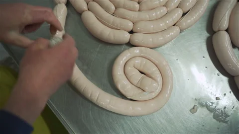 Workers in meat factory forming many short sausages from one long sausage. Stock Footage 131868745