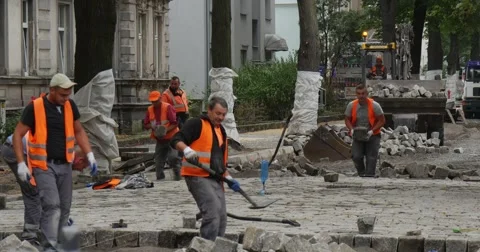 Workers Men in Orange Workwear are Paving the Road with Blocks Working with Stock Footage 54328384