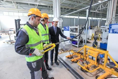 Workers with metal sheet lifting device Stock Photos