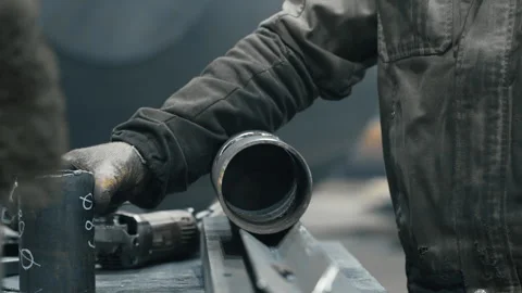 Workers at a metalworking plant try on the dimensions of two pipes. Stock Footage 313104376