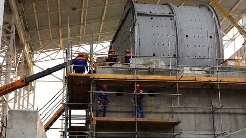 Workers mount a grinding mill for ores of ferrous and non-ferrous metals at a Stock Footage 74110393