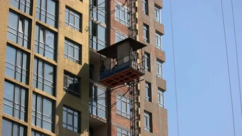 Workers move down on the construction elevator lift. Video stock 194934133