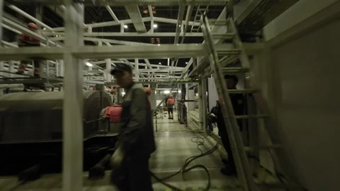 Workers move quickly inside large metallic framework Stock Footage 328948923