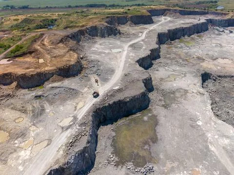 Workers move through a large quarry in an aerial view during daylight Stock Photos