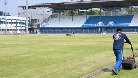 Workers mow and tidy up the grass of a football field Stock Footage 256857517