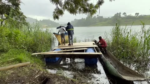 Workers on New Floating Platform beside Dugout Canoe at Lake Bunyonyi, Uganda Stock Footage 348352219