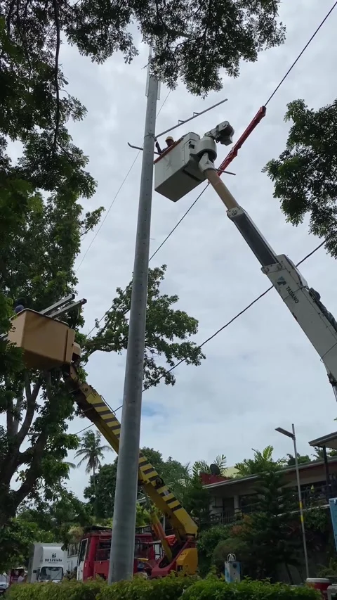 Workers onboard the telescopic crane bucket to fix tall electrical post. Stock Footage 249949758