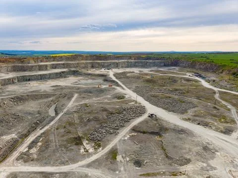 Workers operate machinery in a large mining site covered in dirt and rocks. T 스톡 사진