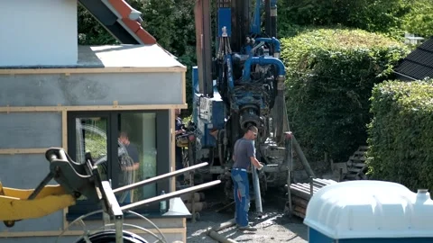 Workers operating a heavy hydraulic drilling rig machine next to a resident.. Video stock 337403114