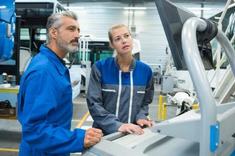 Workers operating a machine in factory Stock Photos