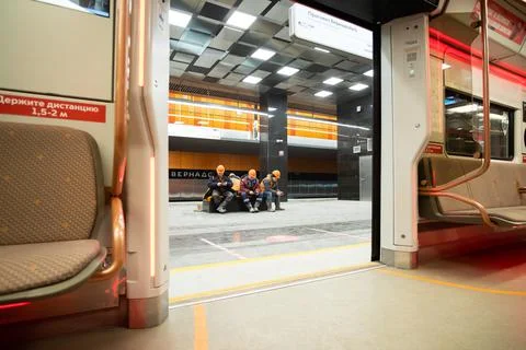 Workers in orange helmets sit on a bench in the lobby of a new metro station Stock Photos