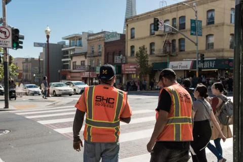 Workers with orange vests wait to cross a street in San Francisco, California Stock Photos