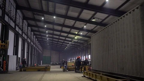 Workers in orange vests walk around the workshop. 4K Stock Footage 104656779